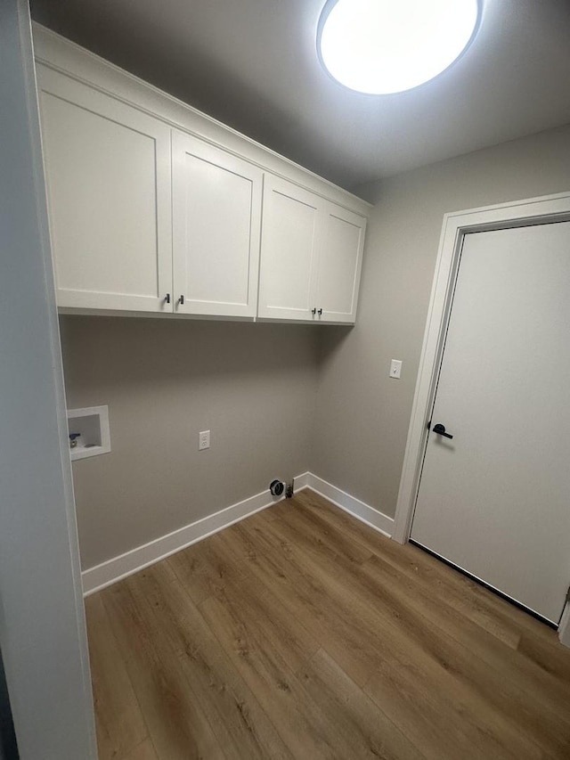 laundry area featuring washer hookup, light hardwood / wood-style floors, and cabinets