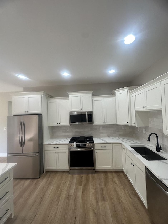 kitchen featuring sink, light wood-type flooring, white cabinets, and appliances with stainless steel finishes