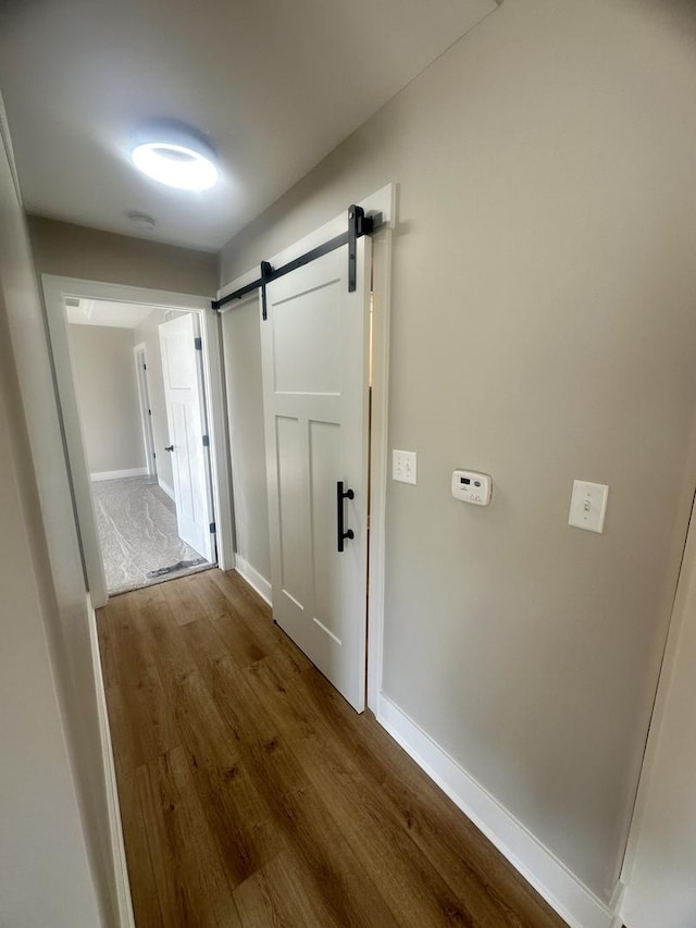 hallway with wood-type flooring and a barn door