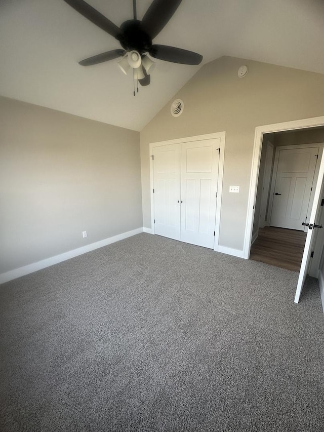 unfurnished bedroom featuring dark colored carpet, lofted ceiling, ceiling fan, and a closet