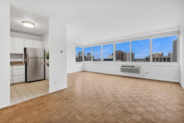 kitchen featuring white cabinets, a wall mounted air conditioner, stainless steel refrigerator, and light parquet flooring