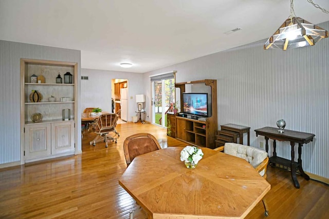 dining room featuring wood-type flooring, vaulted ceiling, and built in features