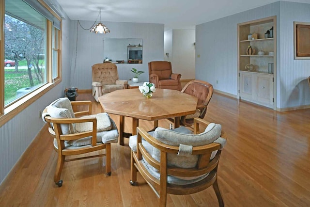 dining space featuring built in shelves, light hardwood / wood-style floors, a wealth of natural light, and a chandelier