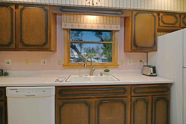 kitchen featuring white appliances, tasteful backsplash, and sink