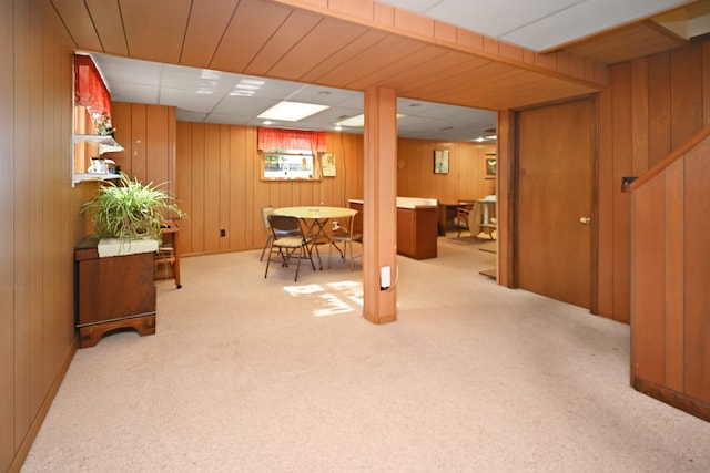 basement featuring light colored carpet and wooden walls