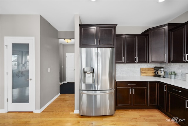 kitchen featuring dark brown cabinetry, light hardwood / wood-style floors, decorative backsplash, and stainless steel fridge with ice dispenser