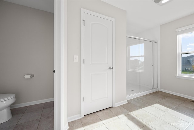 bathroom featuring a shower with door, toilet, and tile patterned flooring