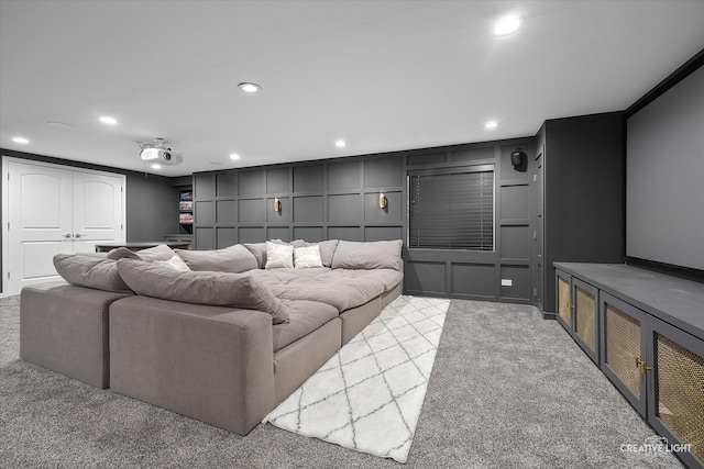 home theater room with ornamental molding and light colored carpet