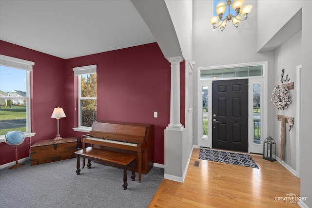 entrance foyer featuring a chandelier, light hardwood / wood-style flooring, and ornate columns