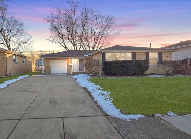 ranch-style home featuring a garage and a lawn