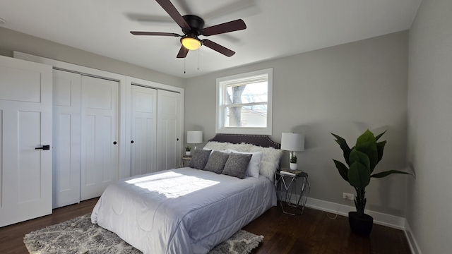 bedroom with ceiling fan, dark hardwood / wood-style floors, and two closets