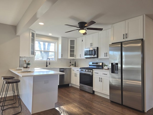 kitchen featuring white cabinets, a kitchen breakfast bar, appliances with stainless steel finishes, and kitchen peninsula