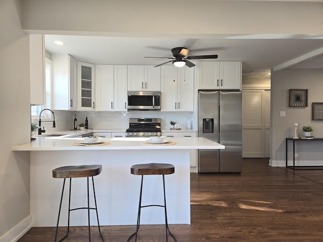 kitchen featuring kitchen peninsula, appliances with stainless steel finishes, white cabinets, and sink