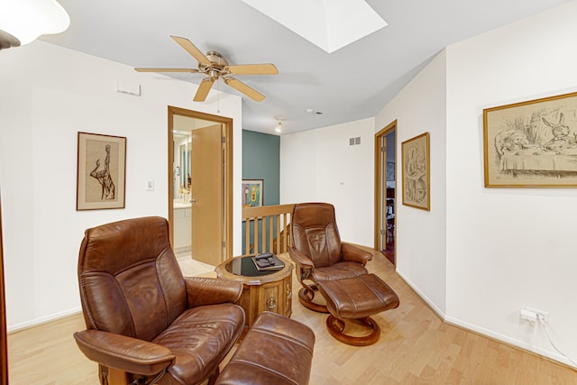 sitting room with light wood-type flooring, a skylight, and ceiling fan