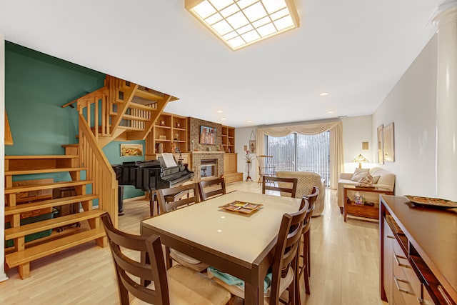 dining area featuring light wood-type flooring and a brick fireplace