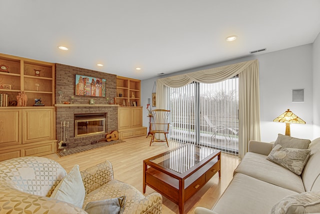 living room featuring a fireplace, built in features, and light hardwood / wood-style flooring