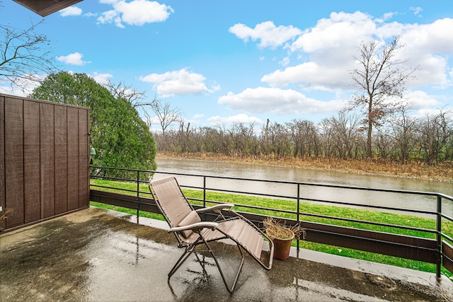 view of patio featuring a balcony and a water view