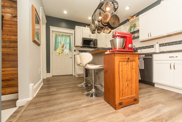 kitchen with appliances with stainless steel finishes, decorative backsplash, white cabinetry, and light hardwood / wood-style flooring