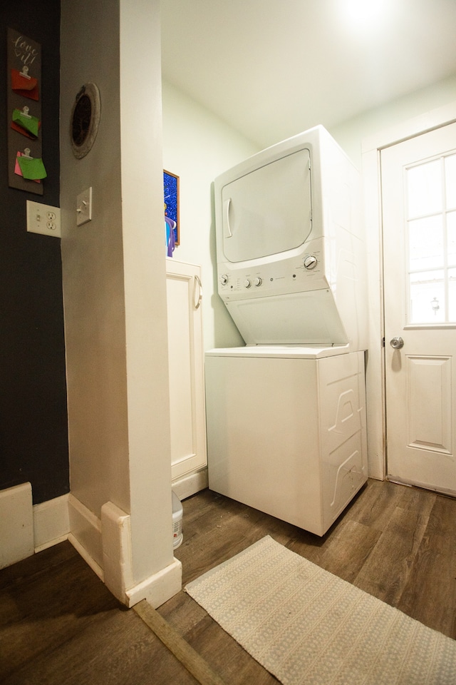 washroom with dark wood-type flooring and stacked washer / dryer