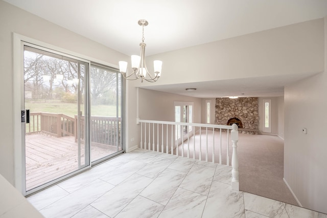 unfurnished dining area with light colored carpet, a chandelier, and a stone fireplace