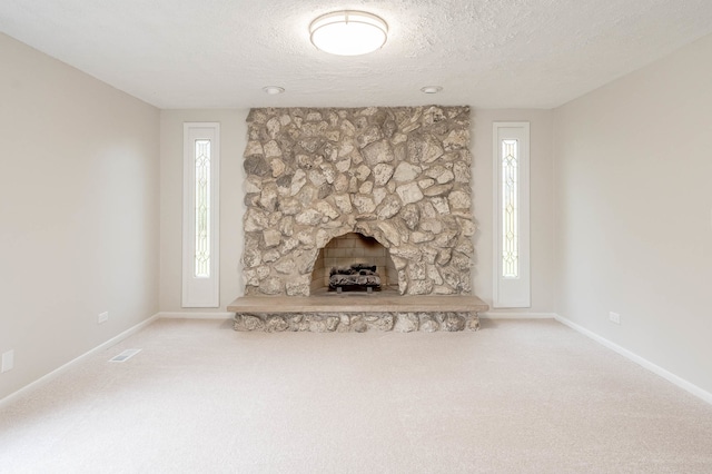 unfurnished living room featuring a fireplace, a textured ceiling, and carpet