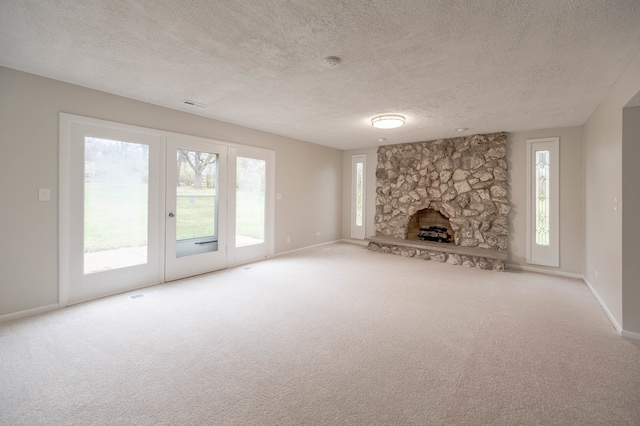 unfurnished living room with a stone fireplace, a textured ceiling, and light colored carpet