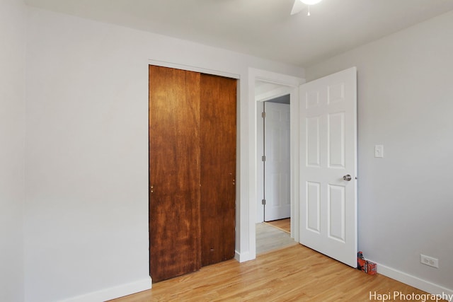 unfurnished bedroom featuring light wood-type flooring, ceiling fan, and a closet