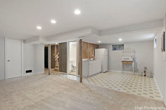 basement with light colored carpet, white fridge, and sink