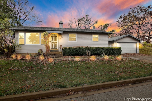 view of front of property featuring a garage, a yard, and an outdoor structure