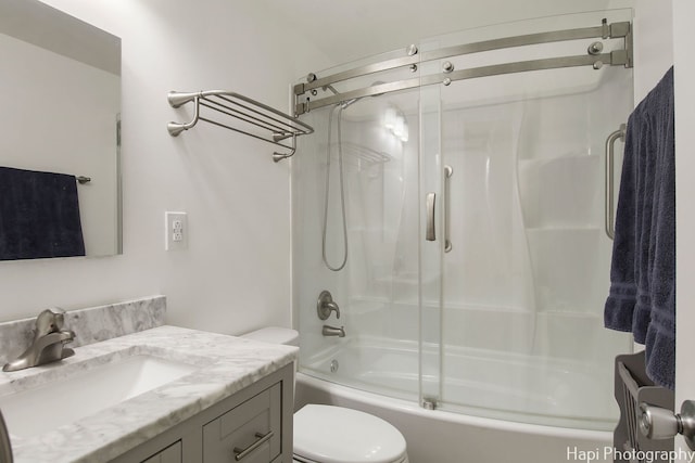 full bathroom with enclosed tub / shower combo, vanity, and toilet