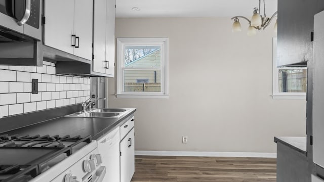 kitchen featuring white cabinetry, sink, backsplash, pendant lighting, and white appliances