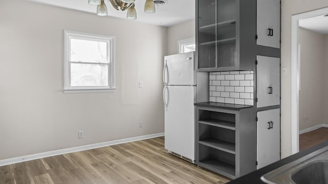 kitchen featuring backsplash, hardwood / wood-style floors, white fridge, and an inviting chandelier