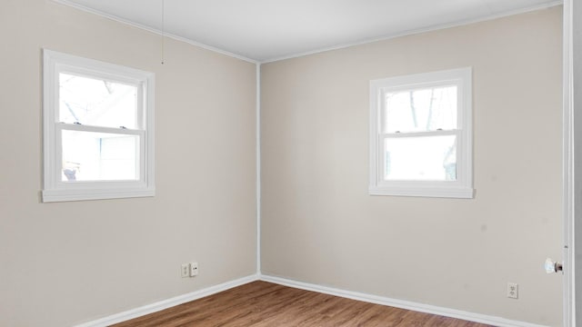 spare room with wood-type flooring, a wealth of natural light, and crown molding