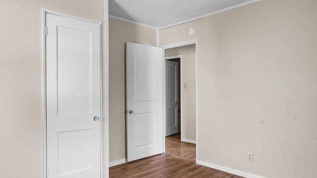 unfurnished bedroom featuring ornamental molding and dark wood-type flooring