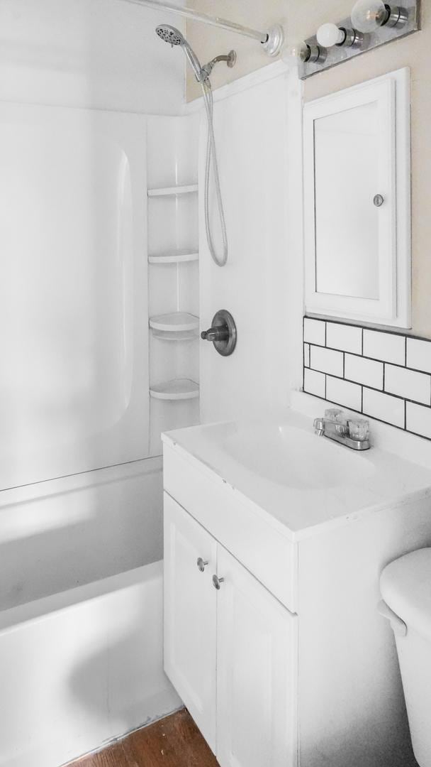 full bathroom featuring vanity, bathtub / shower combination, hardwood / wood-style flooring, decorative backsplash, and toilet