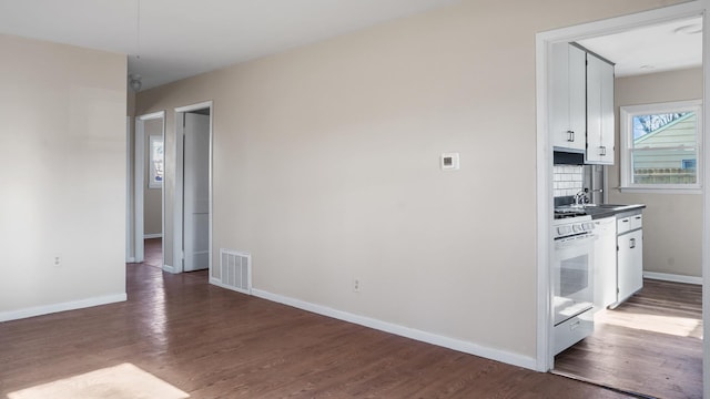 kitchen featuring decorative backsplash, white cabinets, wood-type flooring, and white stove