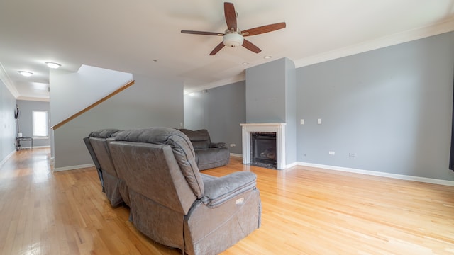 living room with light hardwood / wood-style flooring, ornamental molding, and ceiling fan