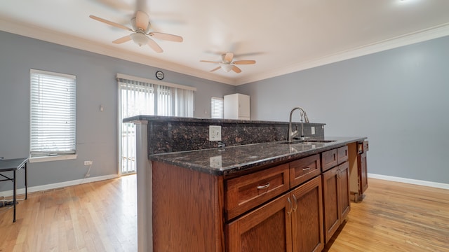 kitchen with light hardwood / wood-style flooring, dark stone counters, sink, crown molding, and ceiling fan