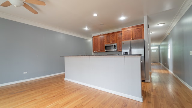 kitchen featuring crown molding, appliances with stainless steel finishes, light hardwood / wood-style floors, and an island with sink