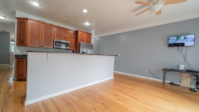 kitchen with light hardwood / wood-style floors, appliances with stainless steel finishes, ornamental molding, and ceiling fan