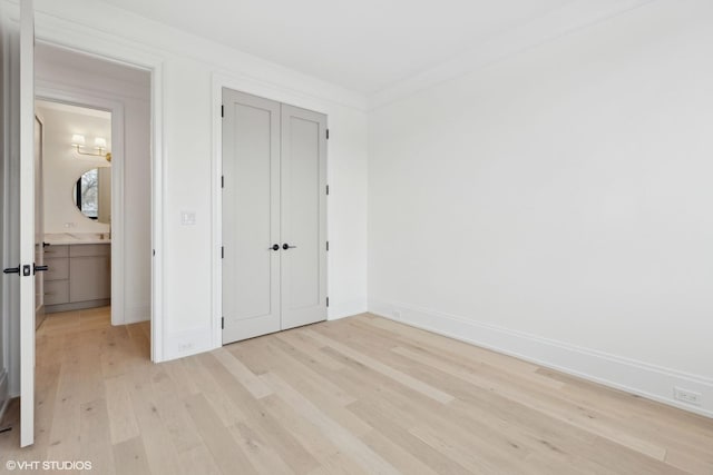 unfurnished bedroom with ornamental molding, light hardwood / wood-style floors, and a closet