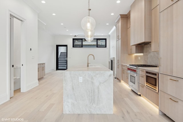 kitchen with an island with sink, sink, light brown cabinetry, and high end range