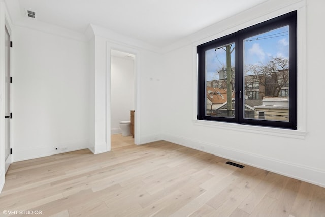 empty room featuring crown molding and light wood-type flooring