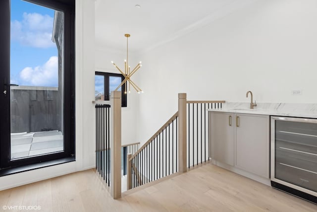 staircase featuring wine cooler, hardwood / wood-style floors, crown molding, and a chandelier