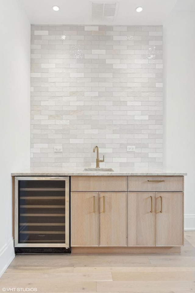 bar featuring light hardwood / wood-style floors, beverage cooler, light brown cabinetry, and sink