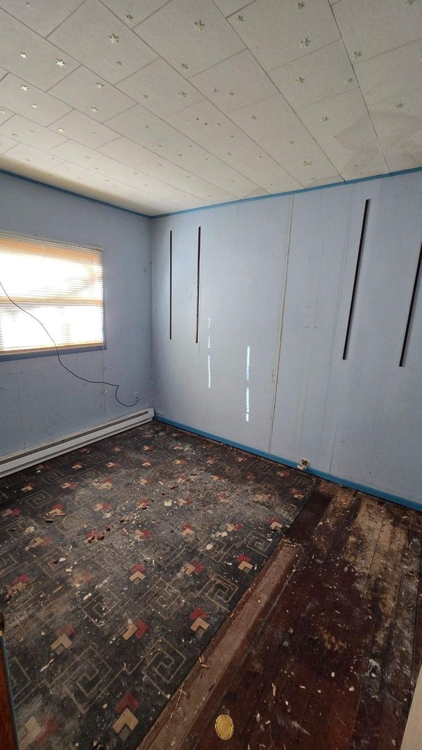 spare room featuring dark hardwood / wood-style flooring and baseboard heating