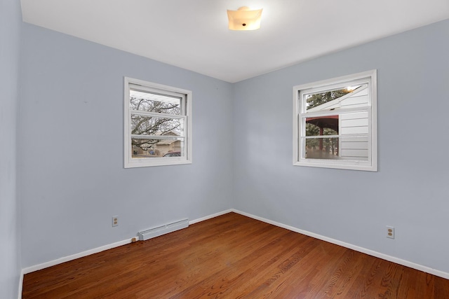 unfurnished room with a baseboard heating unit, hardwood / wood-style floors, and a healthy amount of sunlight