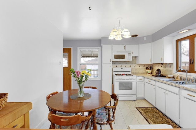 kitchen featuring tasteful backsplash, sink, white cabinets, hanging light fixtures, and white appliances