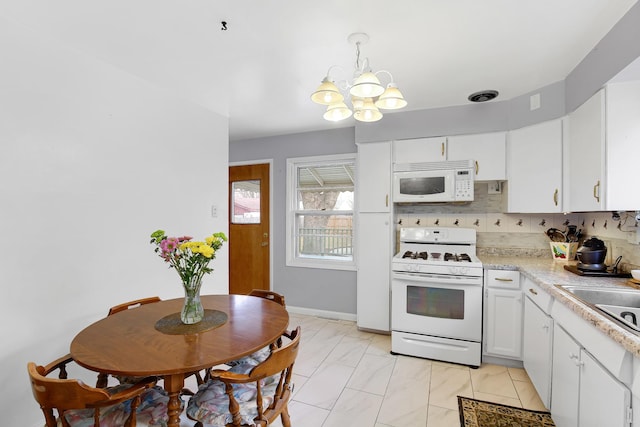 kitchen featuring white cabinetry, sink, backsplash, hanging light fixtures, and white appliances