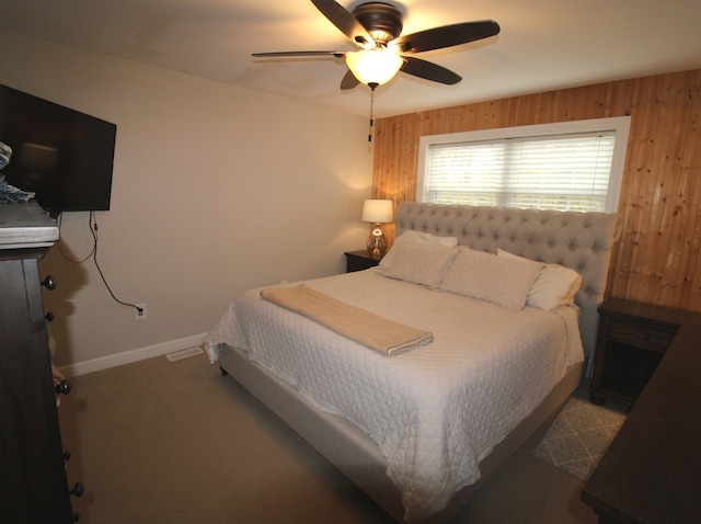 carpeted bedroom featuring wood walls and ceiling fan